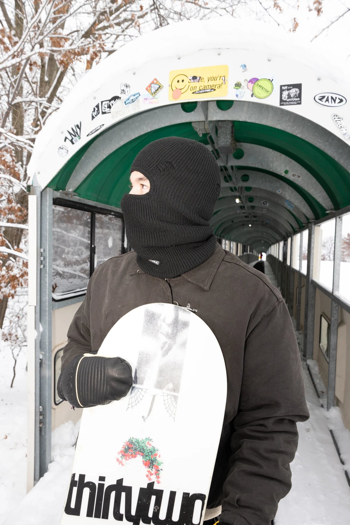 Black Public Snowboards distressed balaclava worn as face protection for snowboarding or winter outdoor activities.