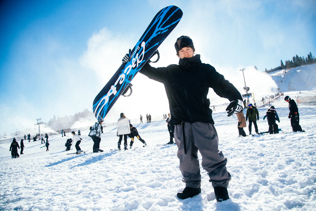 Bataleon Placebo snowboard for men, showcasing its sleek design and binding setup on a snowy landscape.