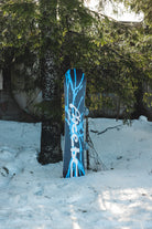Bataleon Placebo snowboard for men, outdoor lifestyle shot showing the all-mountain snowboard with vibrant graphics.