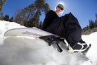 Bataleon Women's Disaster snowboard with colorful design, displayed outdoors on snow, showcasing its shape and vibrant graphics.