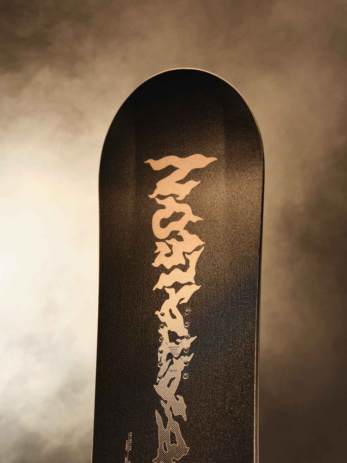 2027 Bataleon Disaster+ snowboard for men, featuring a durable design, shown in a lifestyle setting with snowy mountains in the background.