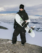 Bataleon Tornado x Beyond Medals snowboard for men, showing the board's design and graphics in a lifestyle setting.