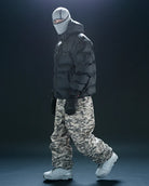 Black Howl Supply puffy men's snow jacket shown from the side with a model wearing camo pants, designed for warmth and style.