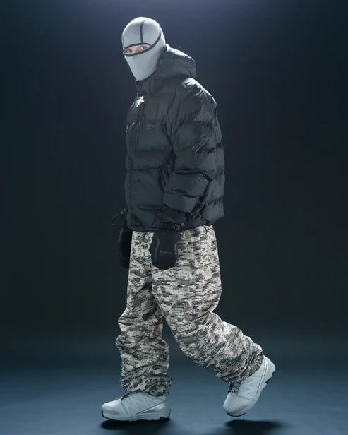 Black Howl Supply puffy men's snow jacket shown from the side with a model wearing camo pants, designed for warmth and style.