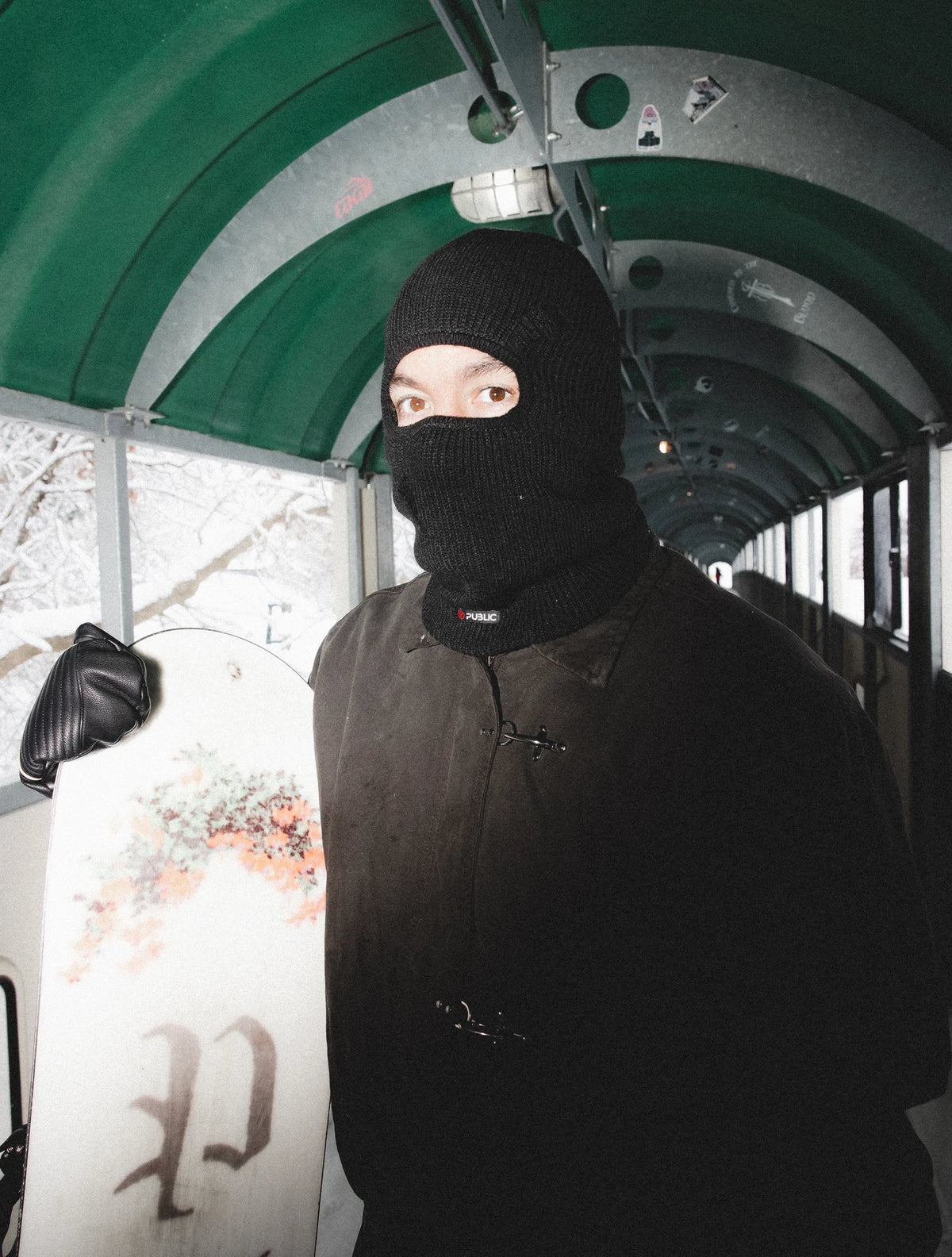 Public Snowboards black distressed balaclava worn as face protection for snowboarding and winter outdoor activities.