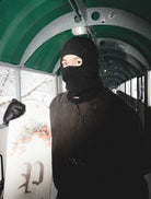 Public Snowboards black distressed balaclava worn as face protection for snowboarding and winter outdoor activities.
