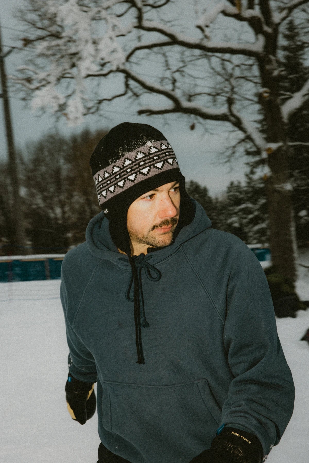 Public Nordic Earflap Beanie in black, stylish winter accessory with earflaps, worn outdoors in a lifestyle setting.