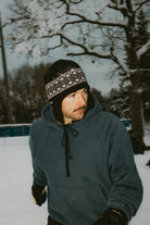 Public Nordic Earflap Beanie in black, stylish winter accessory with earflaps, worn outdoors in a lifestyle setting.