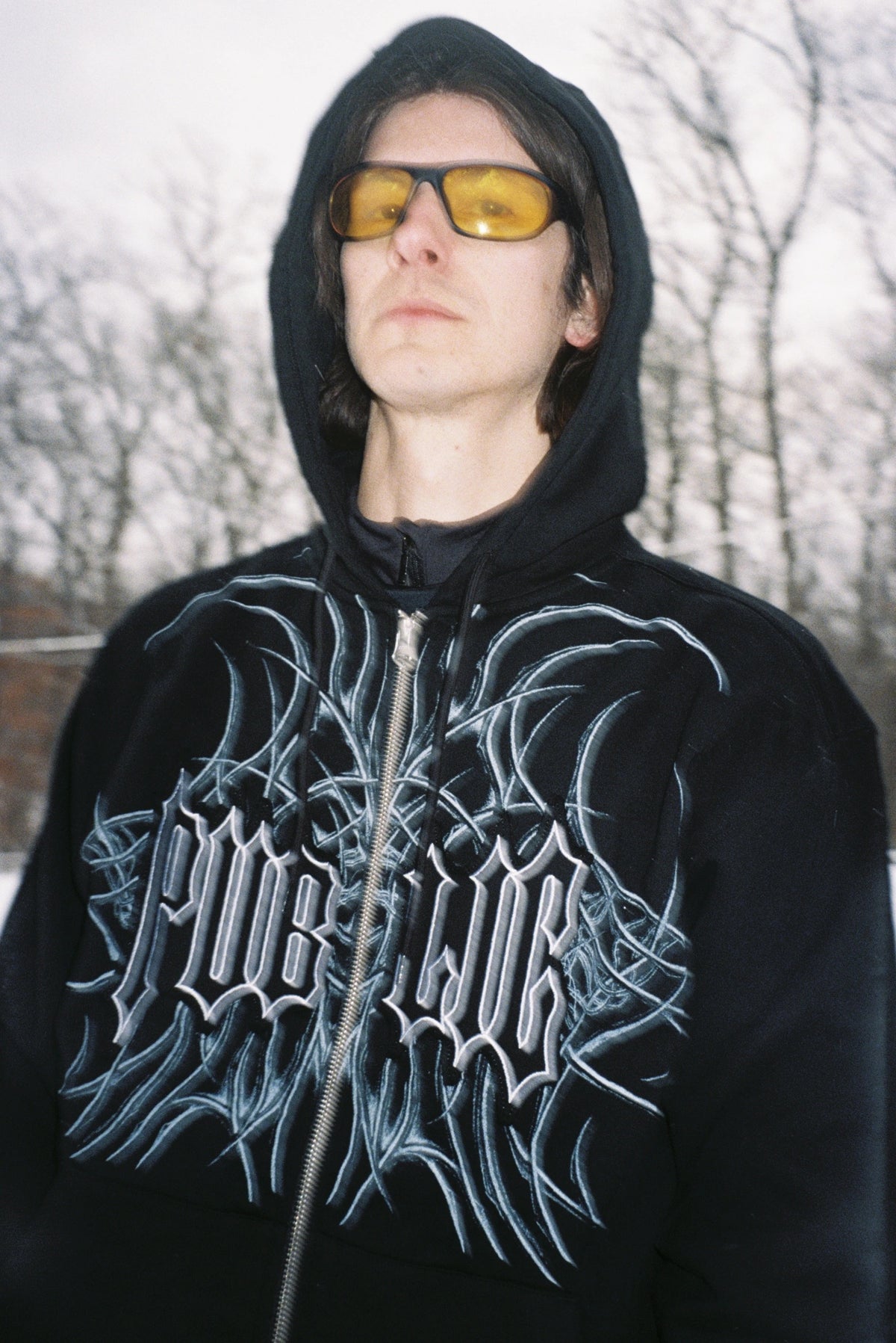 Close-up of black men's Public Snowboards zip-up hoodie, showing the fabric texture and front zipper detail.