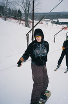 Black men's Public Snowboards zip-up hoodie with a casual fit, featuring a front zipper and hood, ideal for outdoor wear.