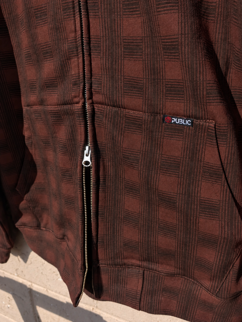 Public Snowboards men's plaid zip-up hoodie in brown, featuring a casual design with a front zipper and comfortable fit.