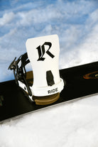 RIDE Drone White snowboard bindings mounted on a snowboard in the snow – view 1