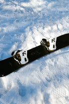 RIDE Drone White snowboard bindings mounted on a snowboard in the snow – view 2
