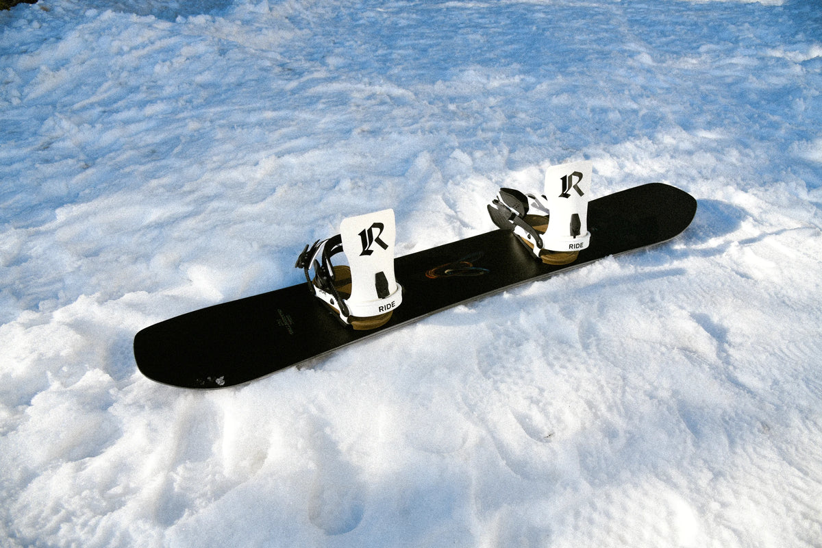 RIDE Drone White snowboard bindings mounted on a snowboard in the snow – view 3