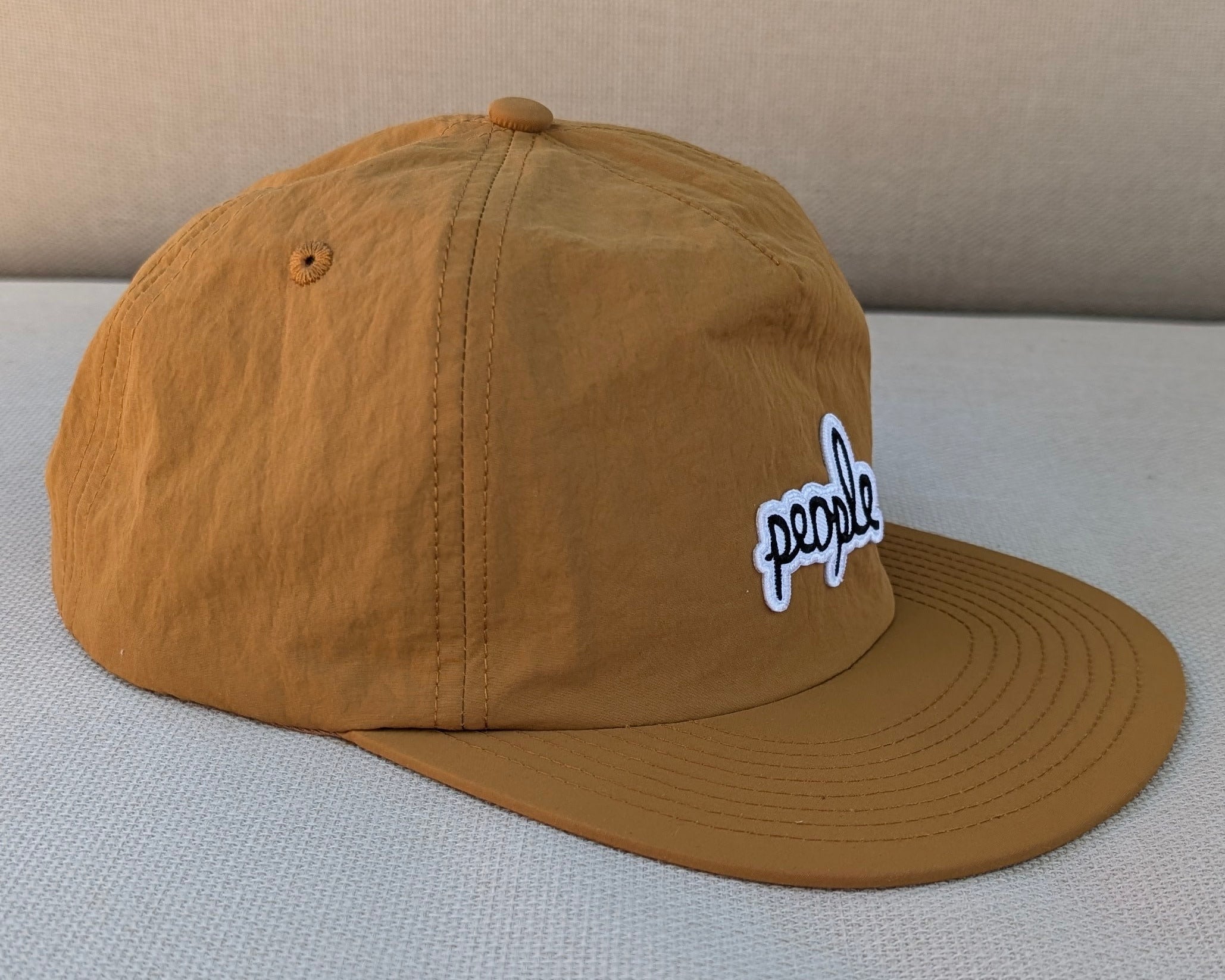 Brown People cap with a logo on a light gray surface